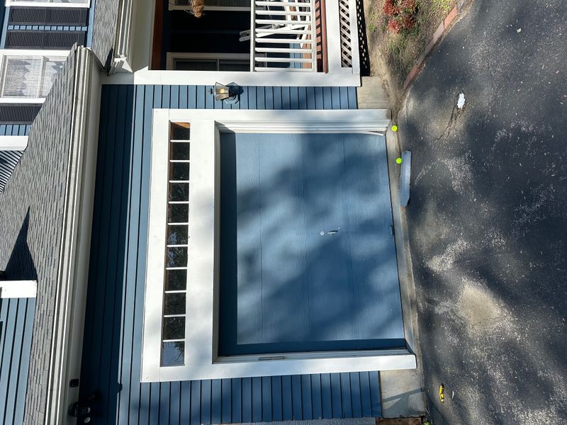 Modern blue flush garage door with side window column on blue colonial home